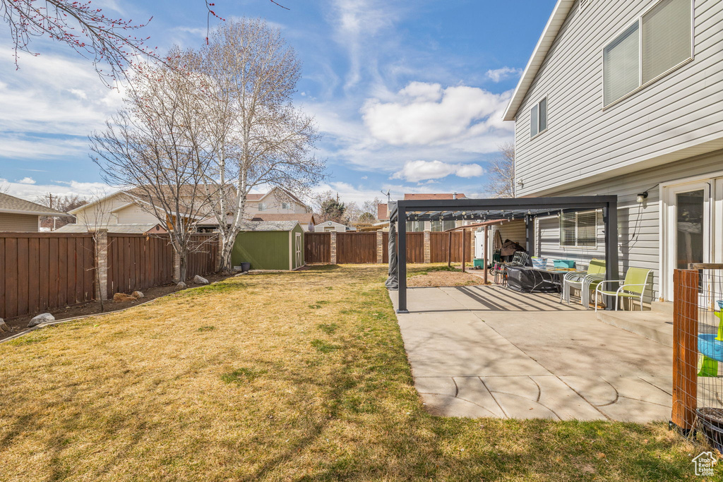View of yard featuring a patio area, a fenced backyard, a shed, and an outbuilding