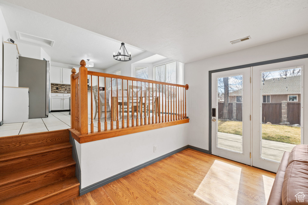 Interior space featuring visible vents, baseboards, light wood-type flooring, and an inviting chandelier