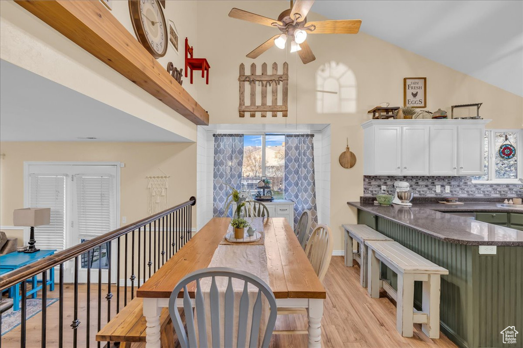 Dining room with light wood-style flooring, high vaulted ceiling, and ceiling fan