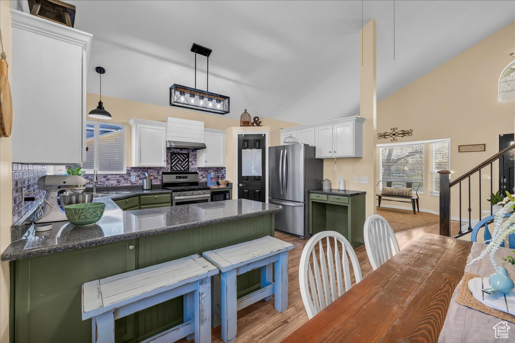 Kitchen with light wood-style flooring, a peninsula, white cabinets, appliances with stainless steel finishes, and decorative backsplash