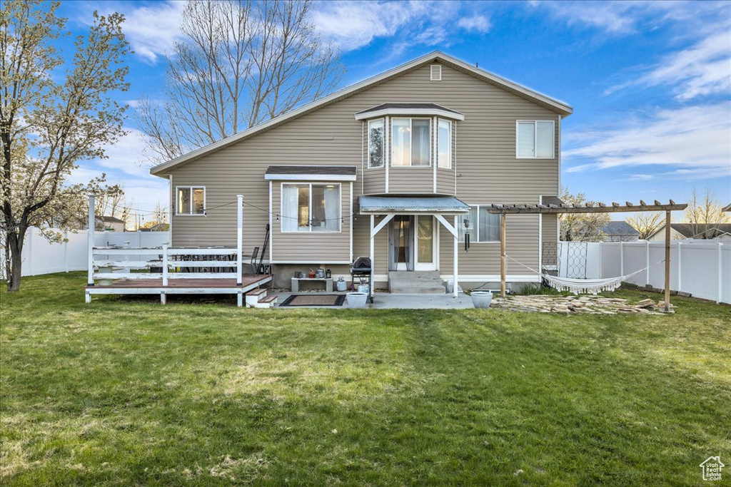 Back of property with a fenced backyard, a pergola, and a lawn