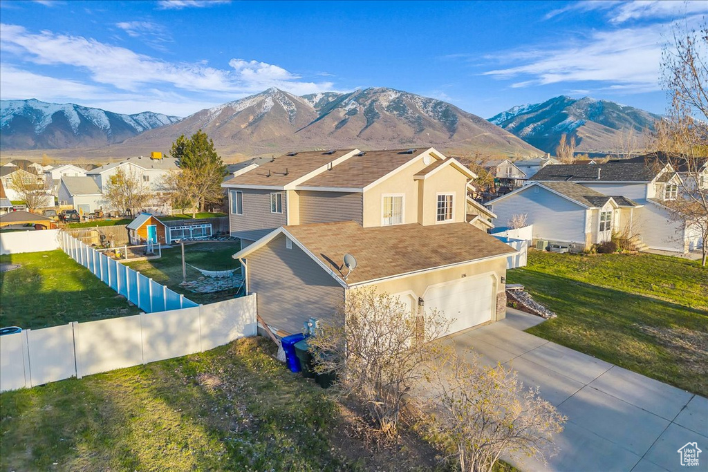 View of front of house with a mountain view, fence, a residential view, and concrete driveway