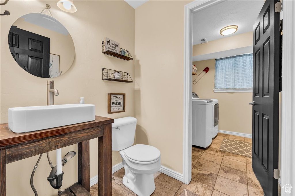 Bathroom with baseboards, toilet, visible vents, washer and dryer, and a sink