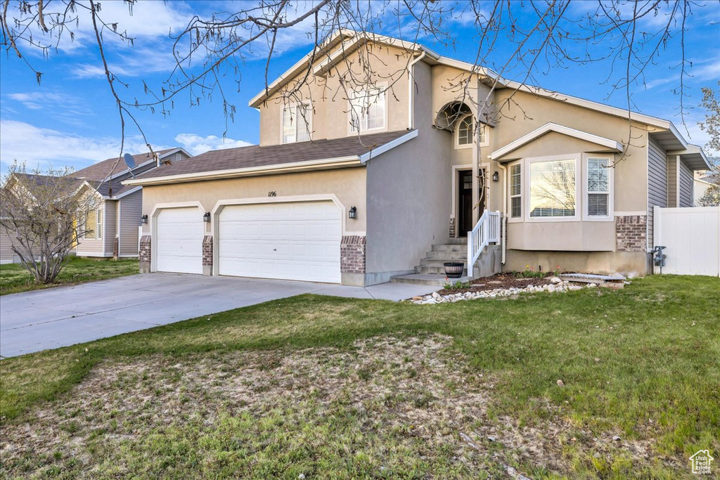 Traditional-style house with concrete driveway, stucco siding, fence, and a front lawn