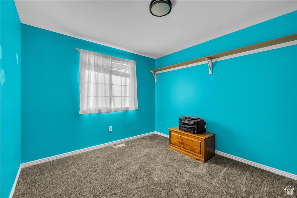 Carpeted empty room with visible vents and baseboards