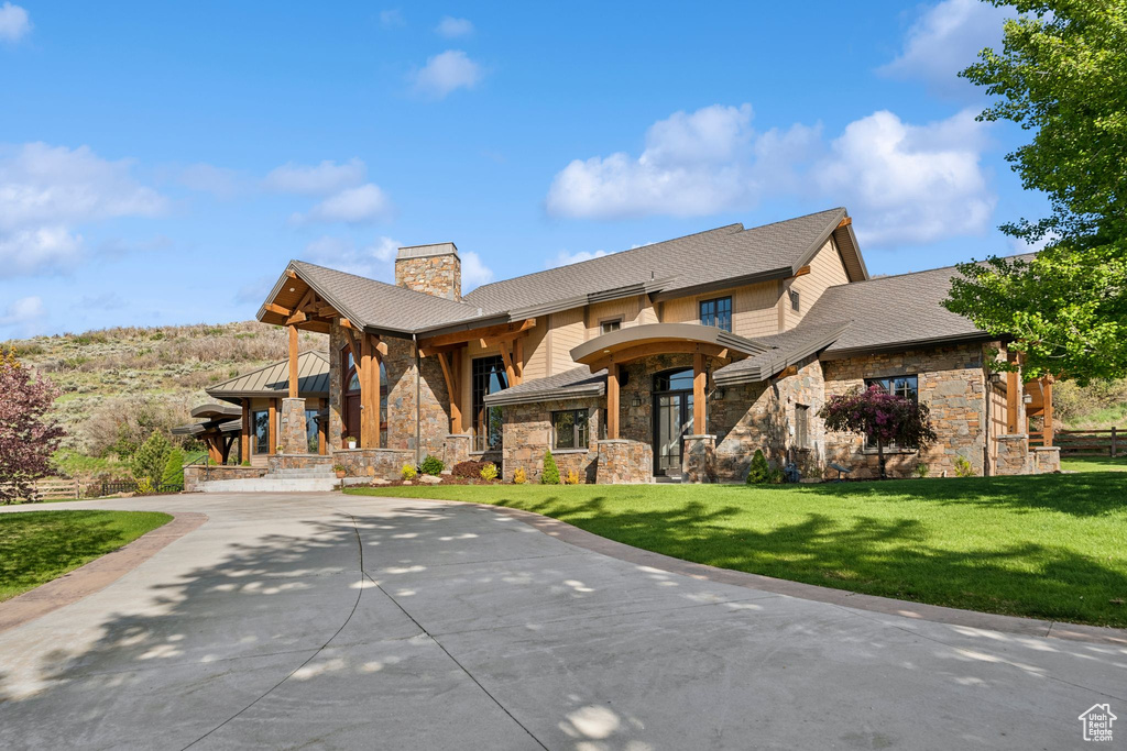 View of front facade featuring stone siding, a chimney, and a front yard