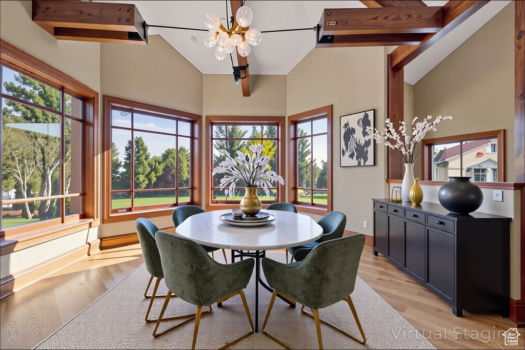 Dining space with a chandelier, light wood-type flooring, plenty of natural light, and a high ceiling