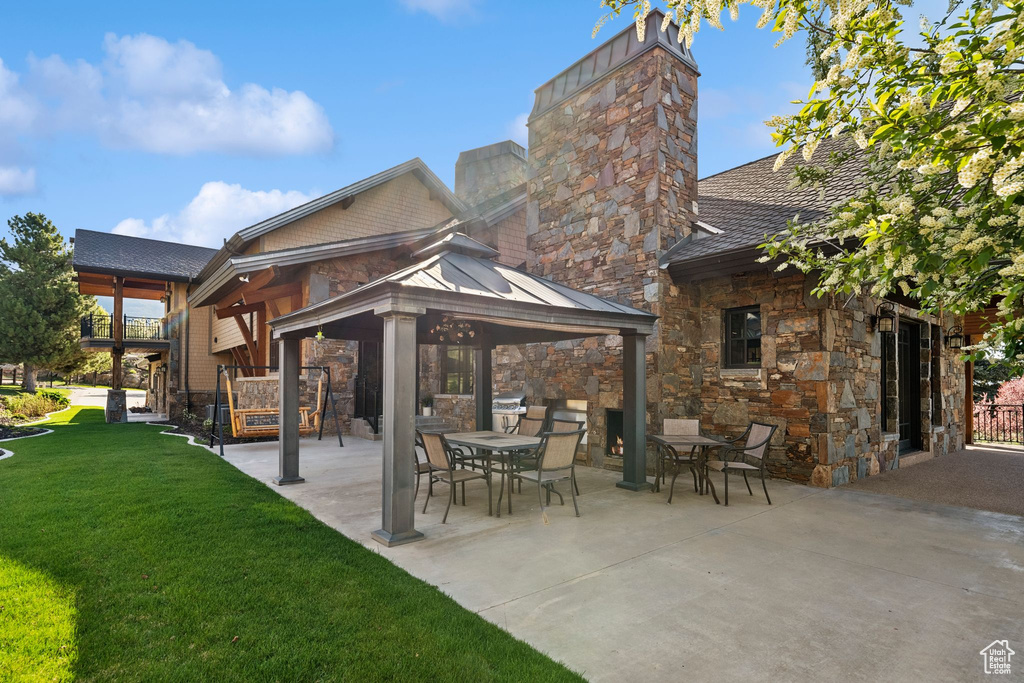 Rear view of property featuring a gazebo, a yard, stone siding, a patio, and a chimney