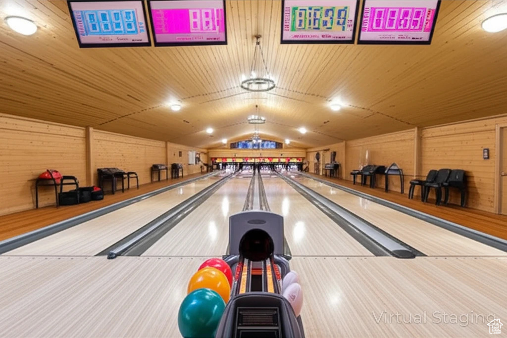 Recreation room featuring bowling, vaulted ceiling, and wooden walls