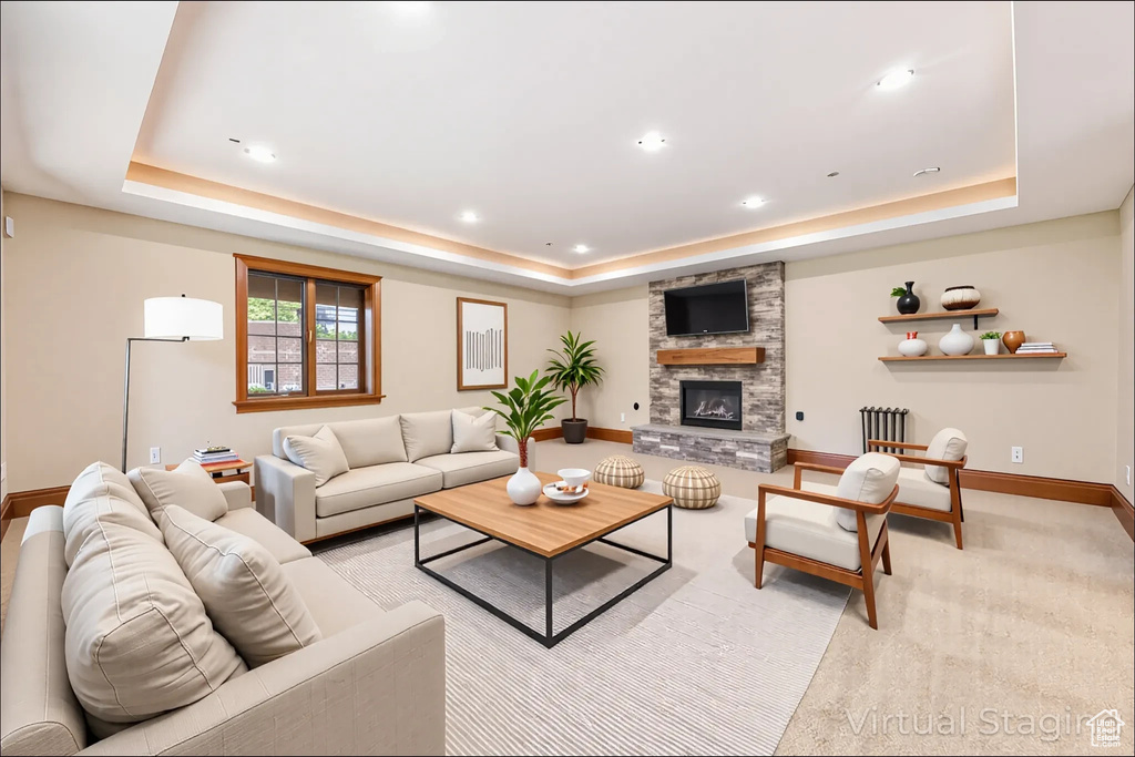 Living room featuring a raised ceiling, a fireplace, and recessed lighting