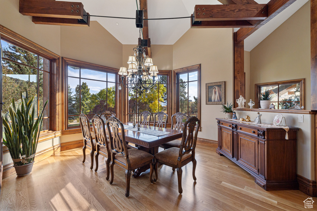 Dining area featuring high vaulted ceiling, a chandelier, and light wood-style floors