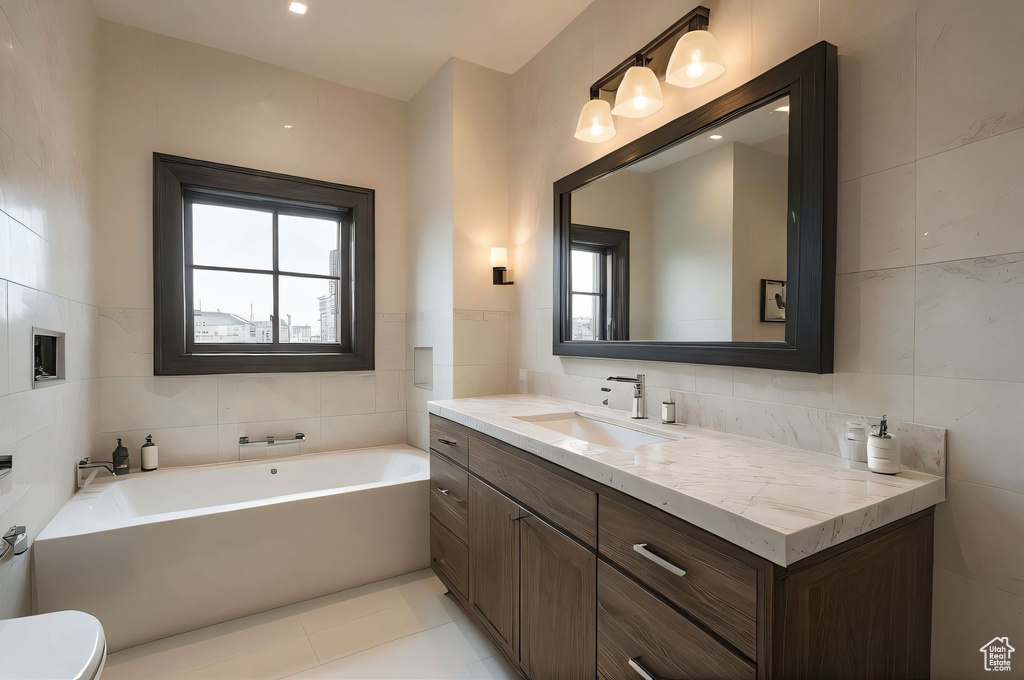 Full bath featuring tile walls, vanity, a bath, and tile patterned floors