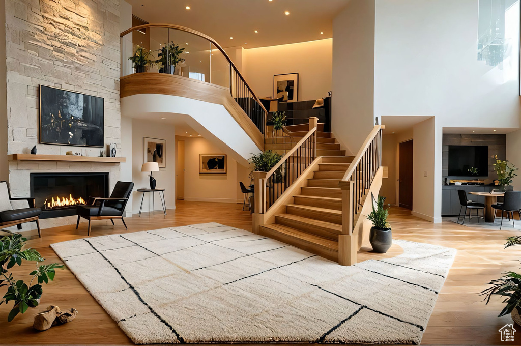 Entrance foyer with a towering ceiling, stairway, a large fireplace, wood finished floors, and recessed lighting