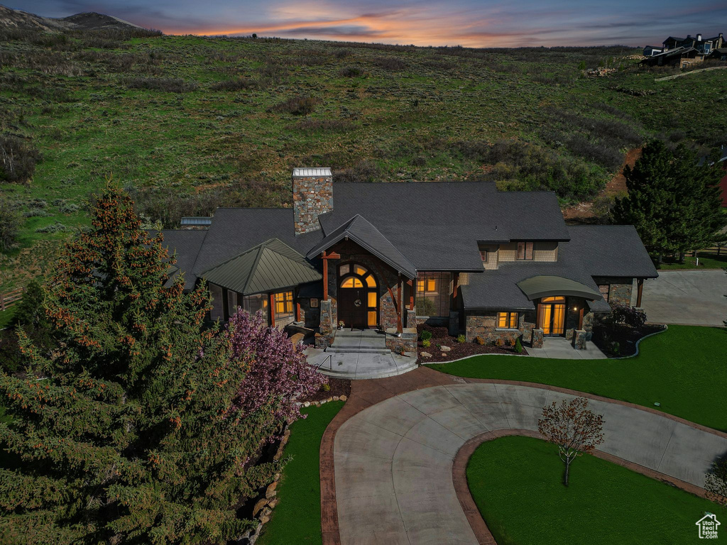 View of front of home featuring stone siding, a chimney, and curved driveway