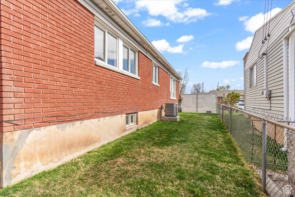 View of property exterior with brick siding, a fenced backyard, and a yard