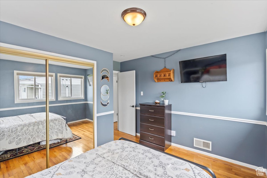Bedroom with visible vents, baseboards, a closet, and wood finished floors