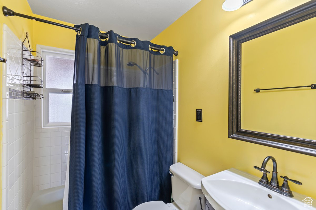 Bathroom featuring toilet, shower / bath combo, and a sink