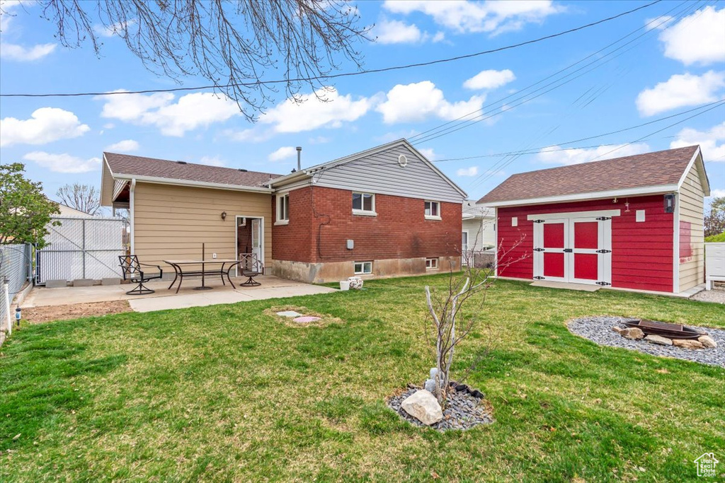 Rear view of house with a shed, a yard, a fenced backyard, an outdoor structure, and a patio area