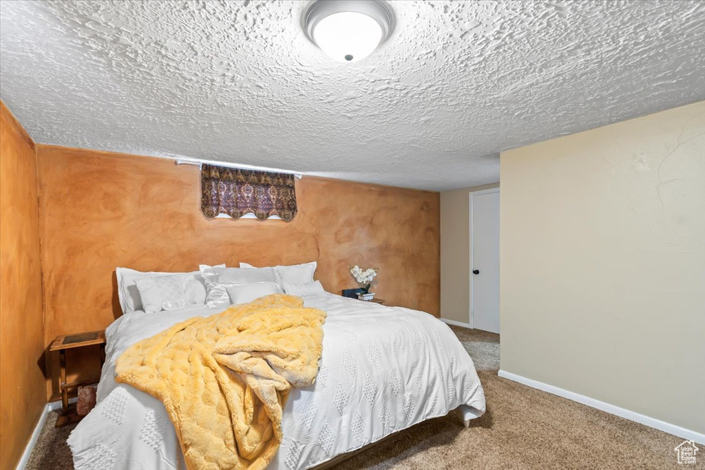 Carpeted bedroom featuring baseboards and a textured ceiling