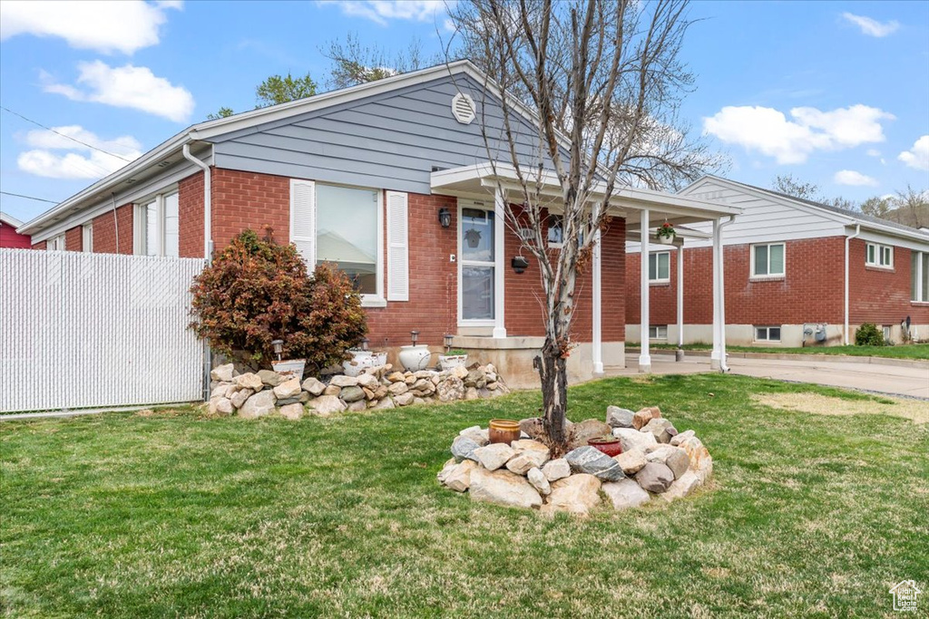 View of front of property featuring brick siding, a front lawn, and fence