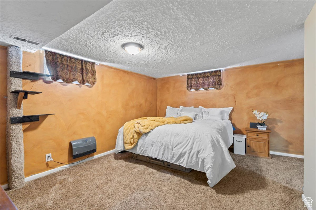 Bedroom with visible vents, baseboards, carpet, and a textured ceiling