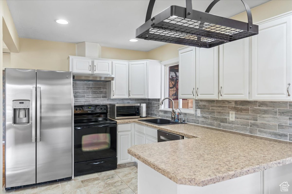 Kitchen with white cabinets, a sink, light countertops, under cabinet range hood, and stainless steel appliances