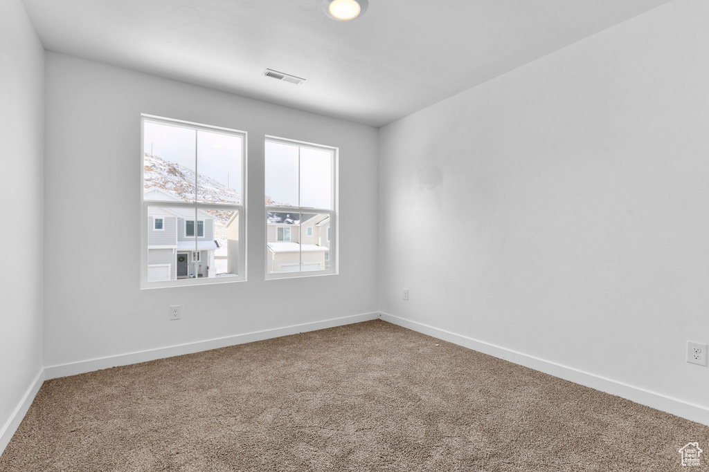 Empty room with carpet floors, baseboards, and visible vents