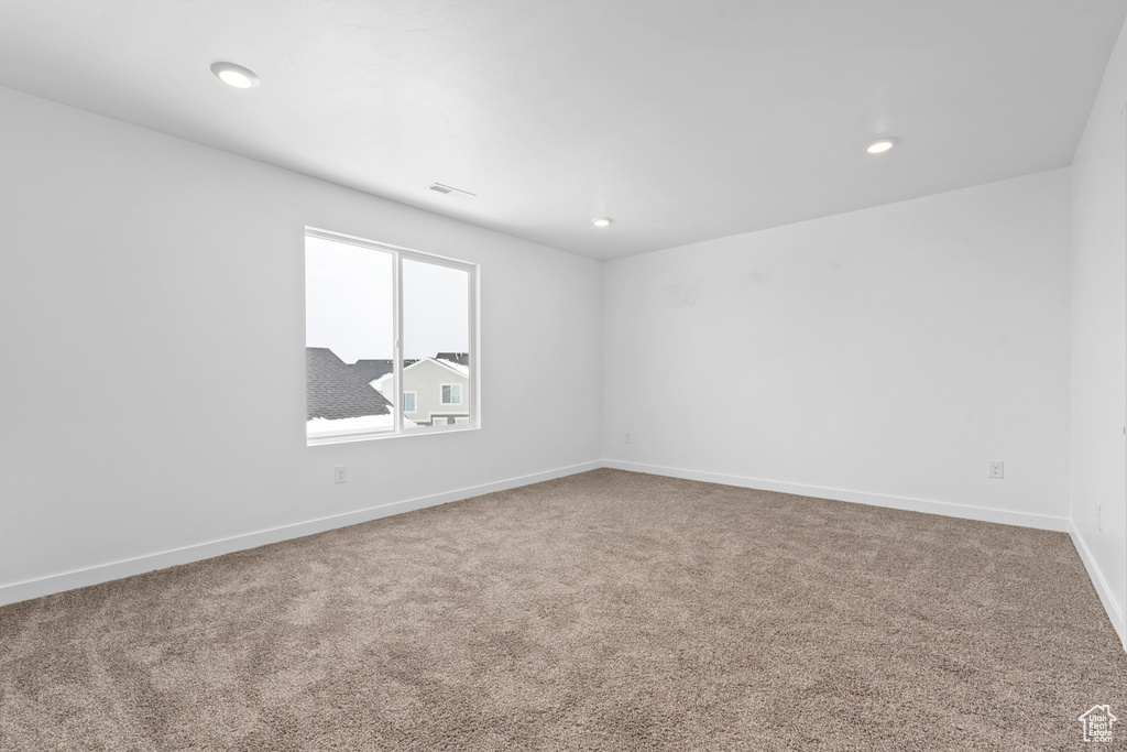 Carpeted empty room featuring baseboards, visible vents, and recessed lighting