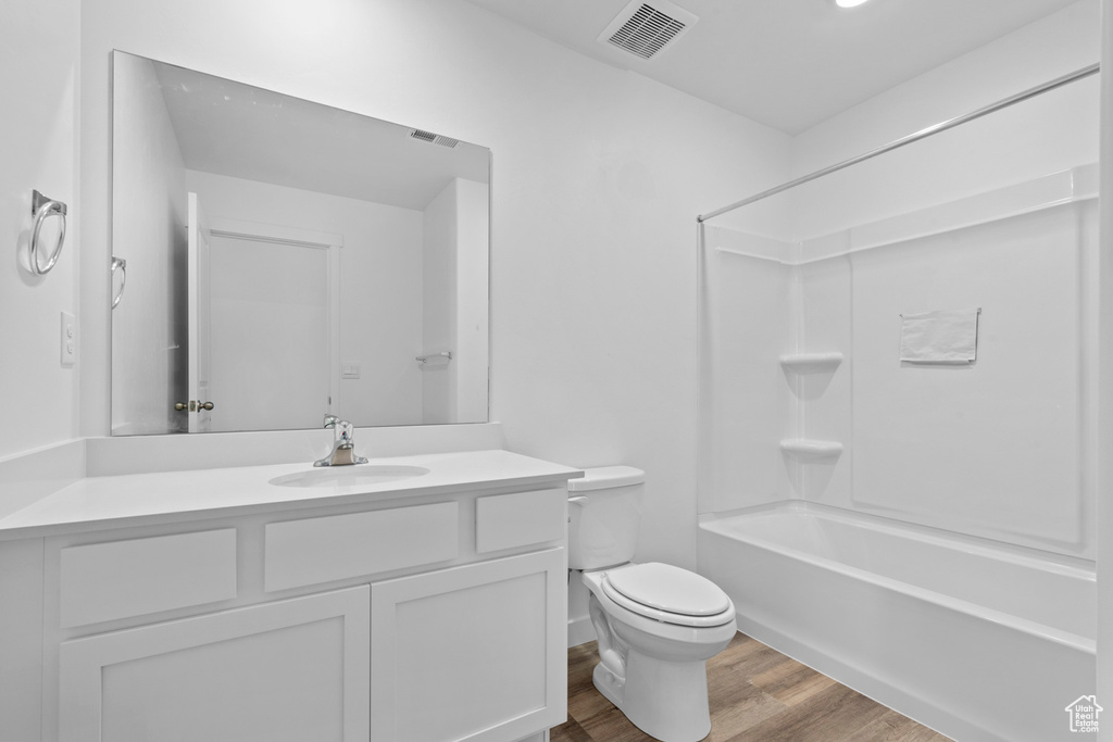 Bathroom with vanity, toilet, visible vents, tub / shower combination, and wood finished floors