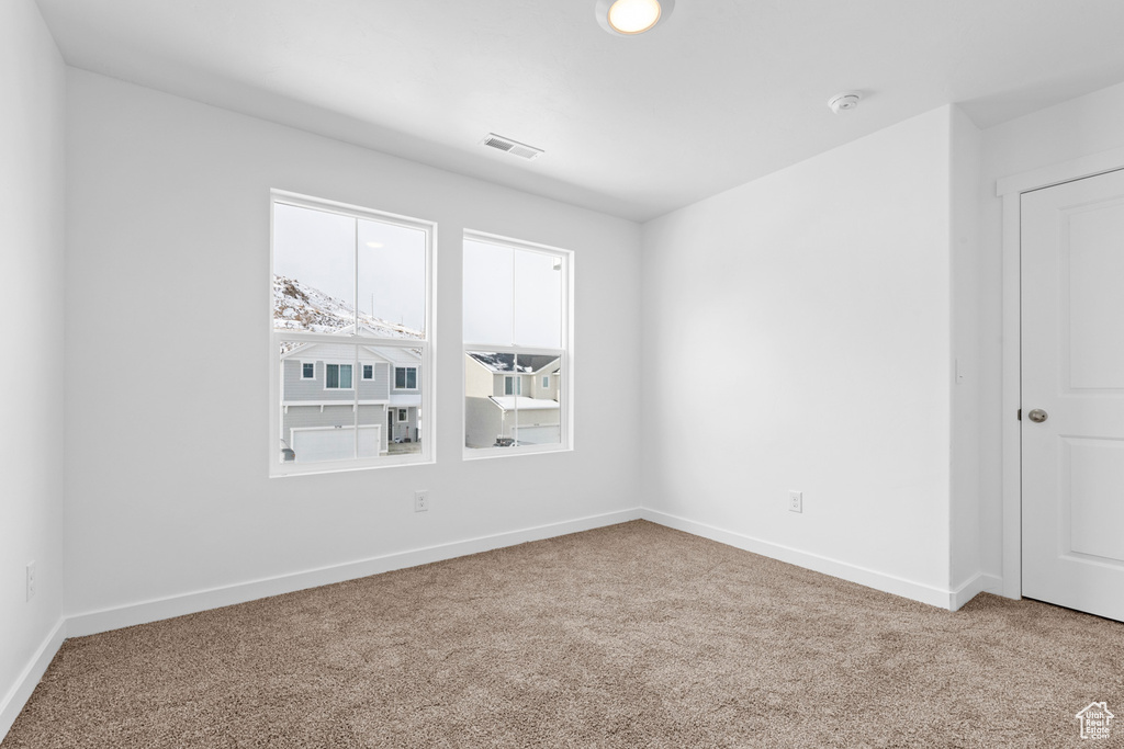 Carpeted spare room with visible vents and baseboards