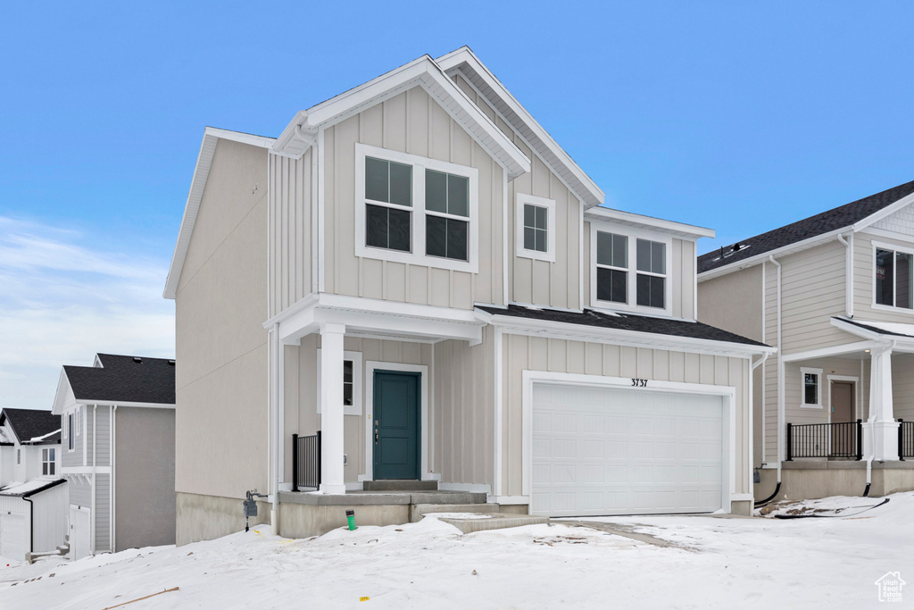 View of front facade with board and batten siding and an attached garage