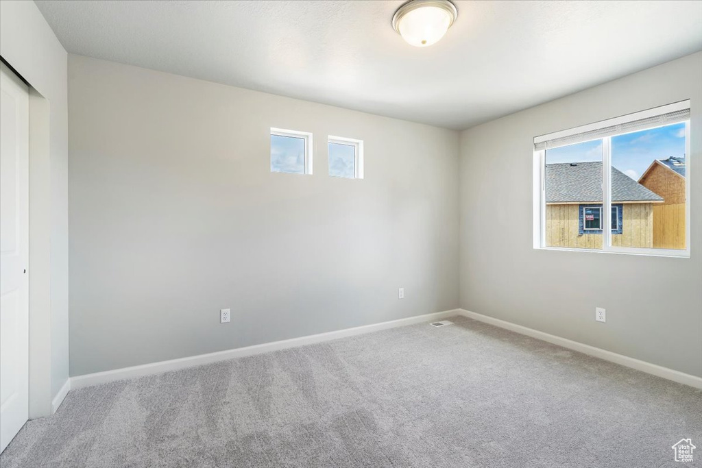 Carpeted spare room with visible vents and baseboards