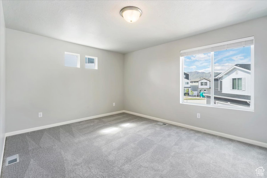 Empty room with carpet flooring, baseboards, and visible vents