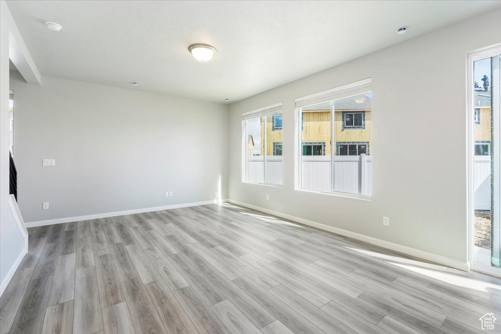 Spare room featuring a wealth of natural light, light wood-style floors, and baseboards