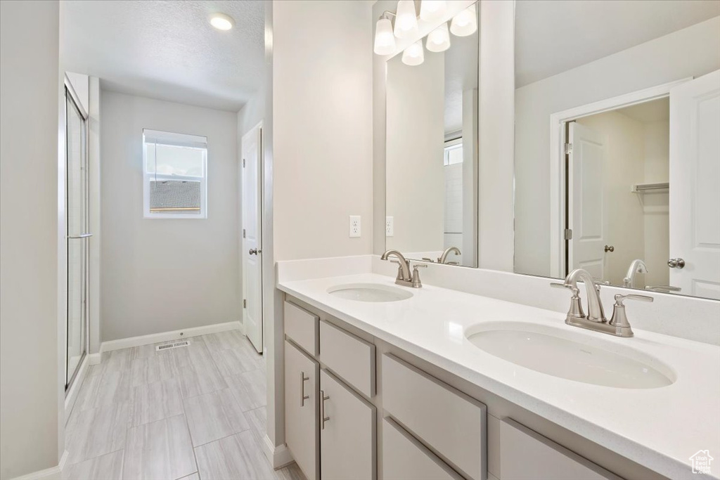 Bathroom with a sink, visible vents, baseboards, and double vanity
