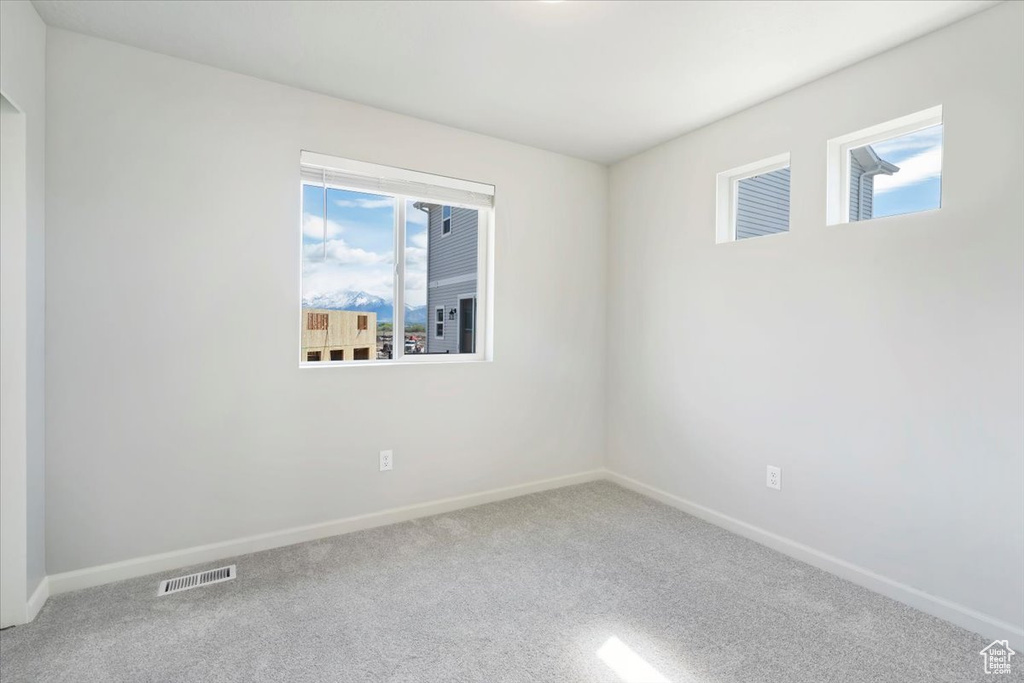 Empty room featuring visible vents, baseboards, carpet, and a healthy amount of sunlight