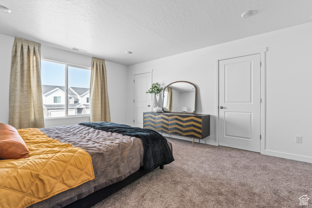Bedroom with a textured ceiling, baseboards, and carpet