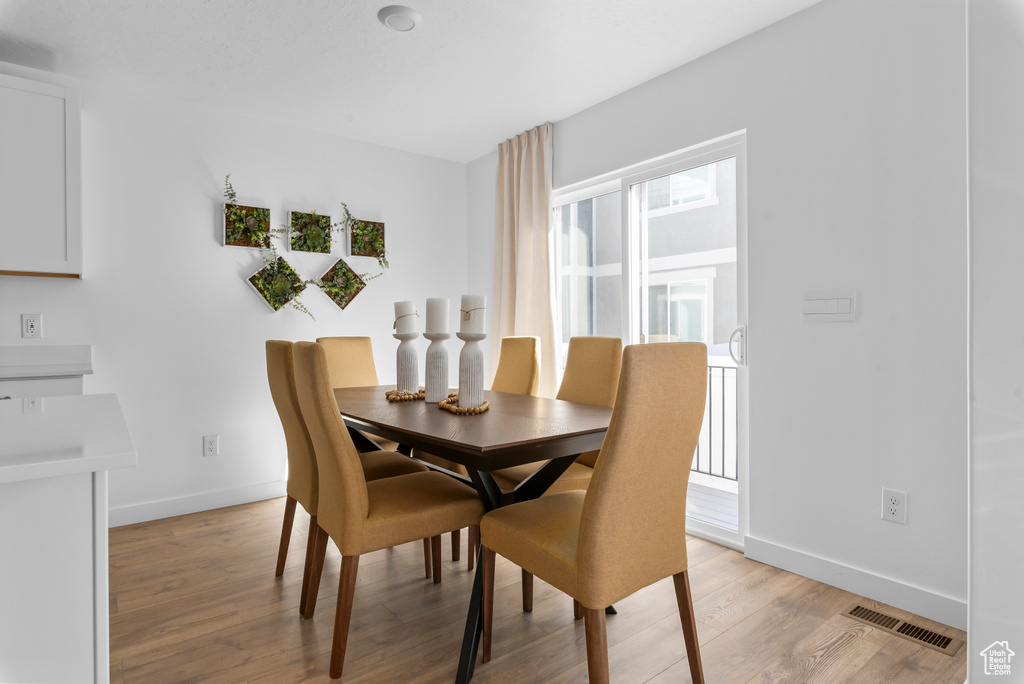 Dining area featuring light wood finished floors, baseboards, and visible vents