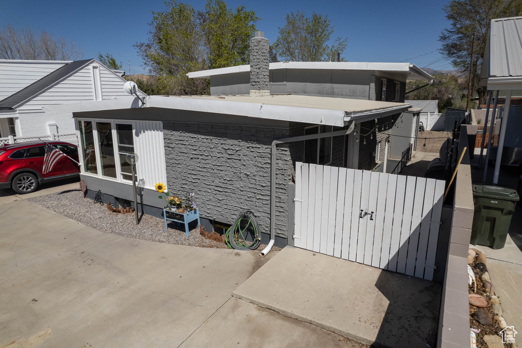 View of side of home featuring fence, a gate, and a chimney