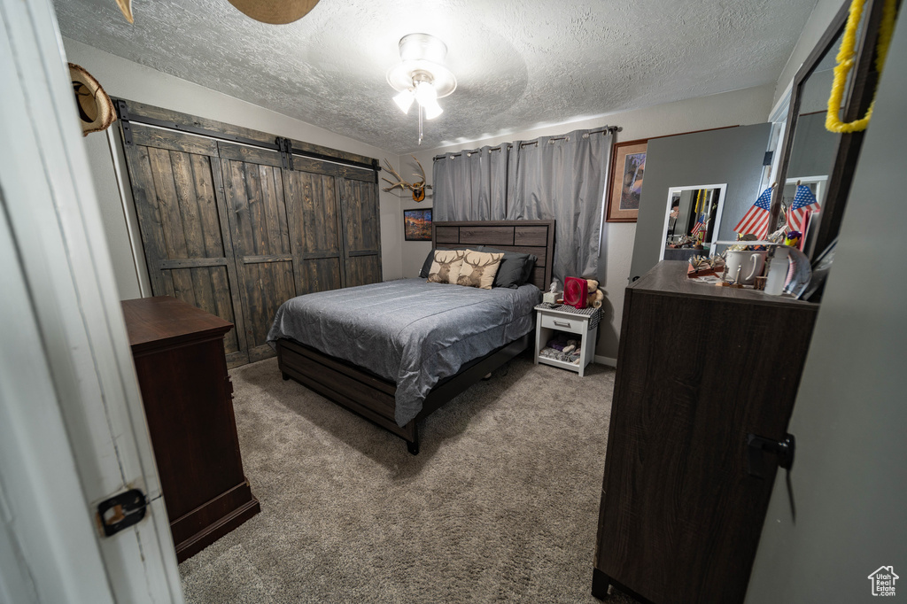 Bedroom featuring carpet flooring, a barn door, and a textured ceiling