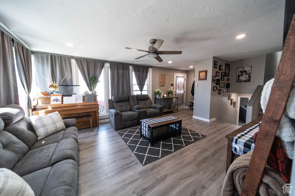 Living room featuring baseboards, recessed lighting, a textured ceiling, a ceiling fan, and wood finished floors