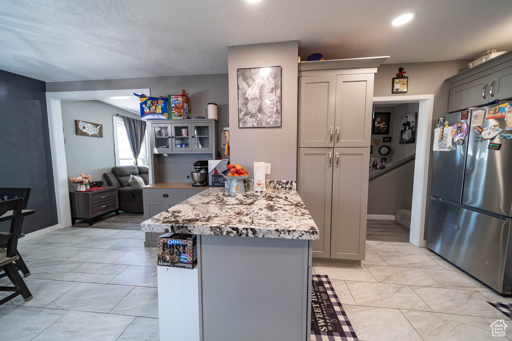 Kitchen with a peninsula, freestanding refrigerator, and gray cabinets