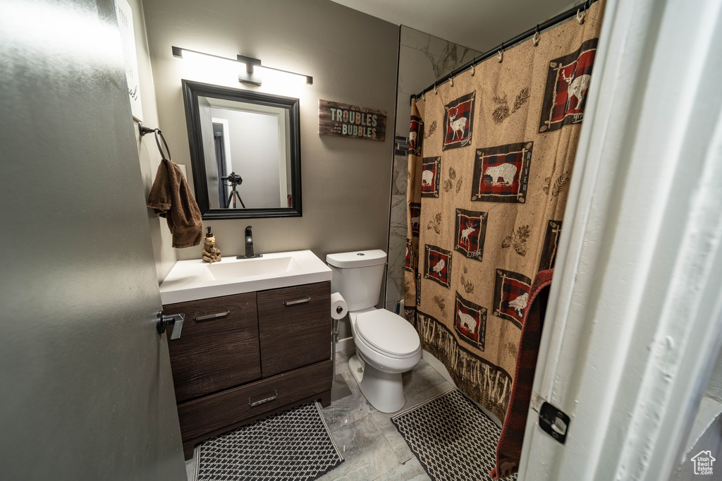 Full bathroom featuring curtained shower, vanity, and toilet