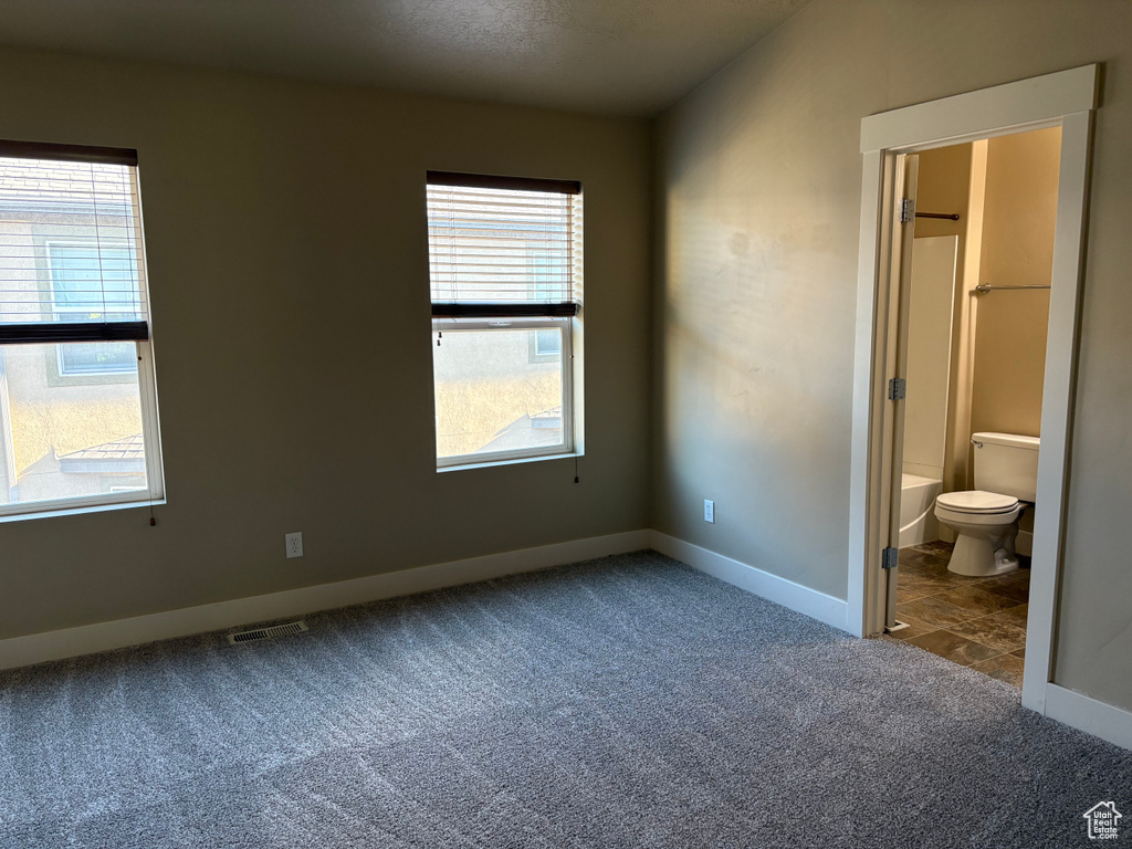 Unfurnished bedroom with carpet floors, baseboards, and ensuite bathroom