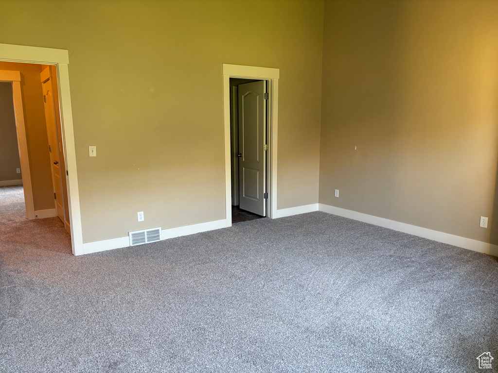 Empty room featuring dark colored carpet and baseboards