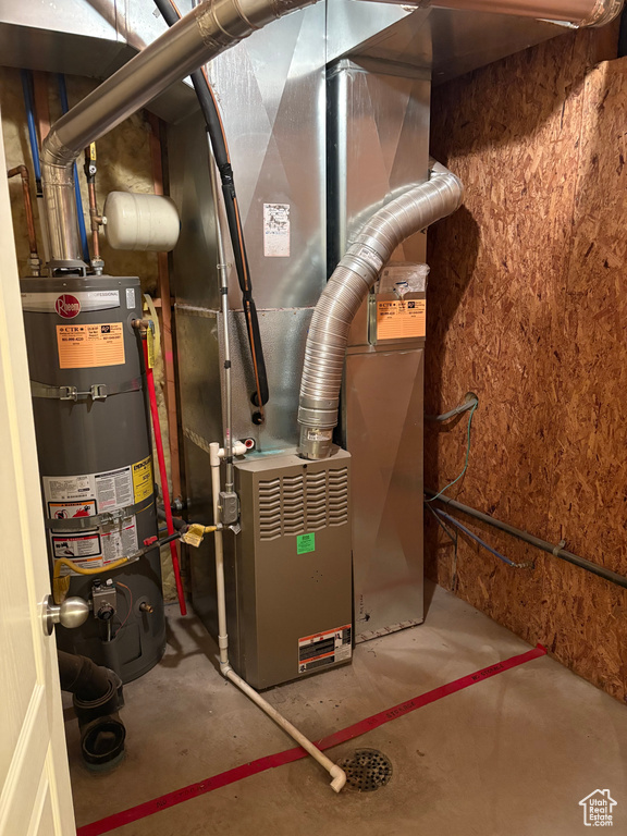 Utility room featuring strapped water heater and heating unit