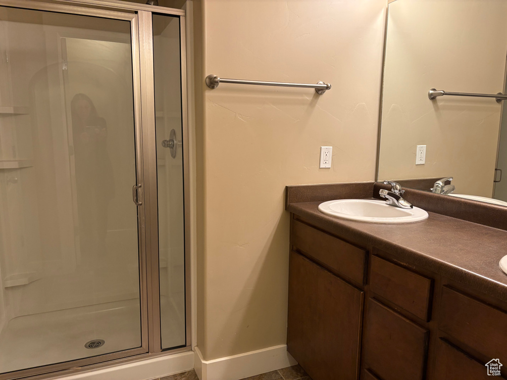 Bathroom with a stall shower, vanity, and baseboards