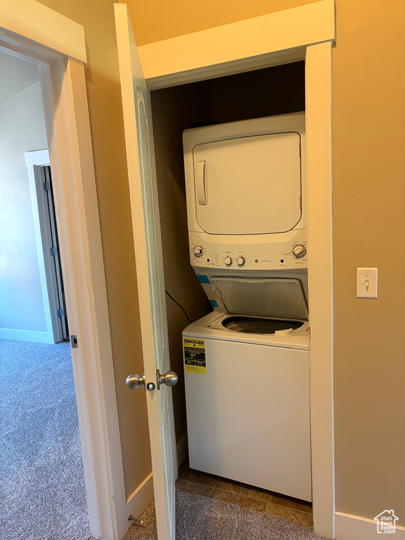 Washroom with stacked washer / drying machine and dark carpet