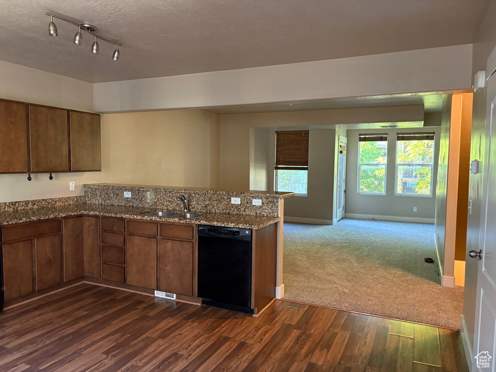 Kitchen featuring dishwasher, a sink, a peninsula, dark wood-type flooring, and open floor plan