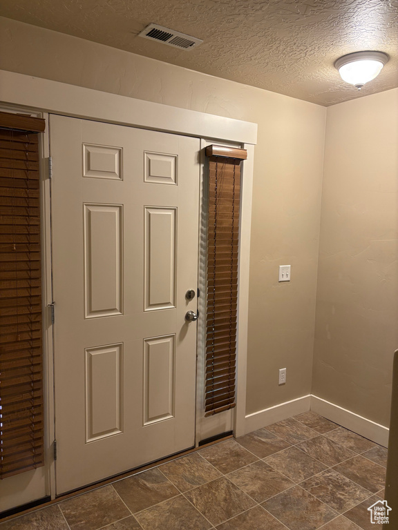 Entryway with a textured ceiling and baseboards